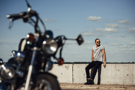 selective focus of young biker with classic motorcycle on foregroundの写真素材