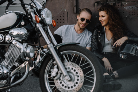 couple of bikers sitting on asphalt with chopper motorcycleの写真素材