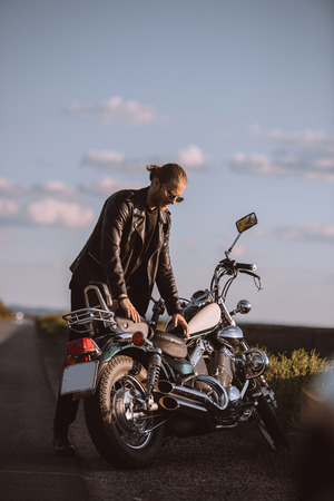 handsome male biker with classical motorcycle on roadの写真素材