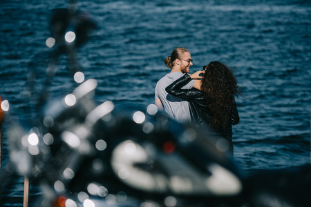 bikers hugging near the sea with motorcycle on foreground