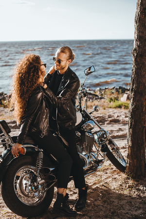 couple of bikers embracing on classic motorcycle on seashoreの写真素材