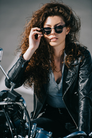 beautiful curly girl in sunglasses sitting on motorbikeの写真素材