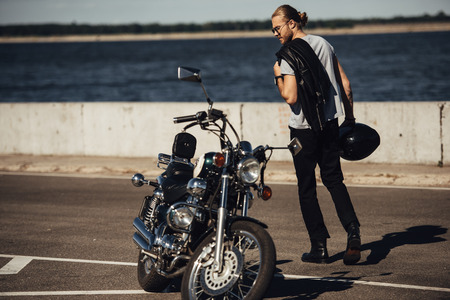 young biker with chopper motorcycle in city with riverの写真素材