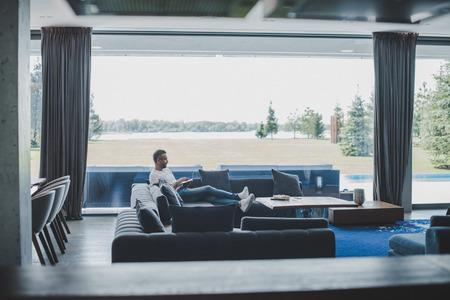 distant view of male freelancer working with laptop on sofa at homeの写真素材