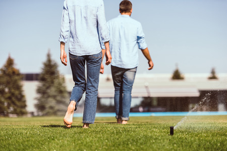partial view of couple waking on green lawn near country houseの写真素材