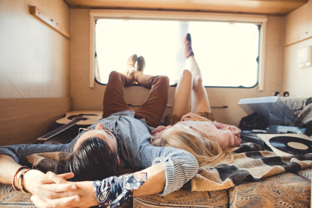 hippie couple lying inside campervan with acoustic guitar and vinyl playerの写真素材