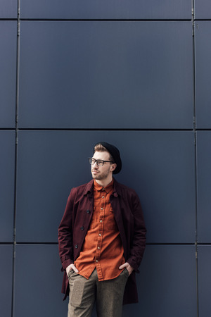 handsome fashionable man standing at black wallの写真素材
