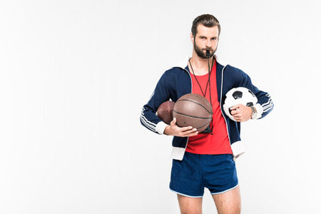 sportive coach with whistle holding rugby, basketball and soccer balls, isolated on white