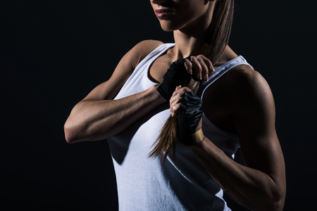 cropped view of muscular sportswoman posing in sportswear, isolated on blackの写真素材