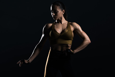 beautiful strong bodybuilder posing and showing muscles, isolated on blackの写真素材