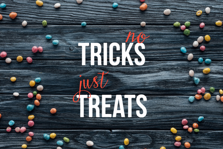 elevated view of arranged colorful delicious candies on wooden background  with "no tricks just treats" letteringの写真素材
