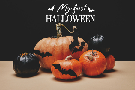 orange and black pumpkins with paper bats on table with bats and "my first halloween" letteringの写真素材