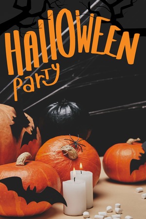 pumpkins with paper bats and spider web on table with "halloween party" letteringの写真素材