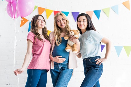 smiling multicultural friends and pregnant woman looking at camera at baby-partyの写真素材