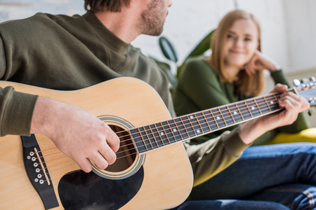 cropped shot of man playing on acoustic guitar to smiling girlfriendの写真素材