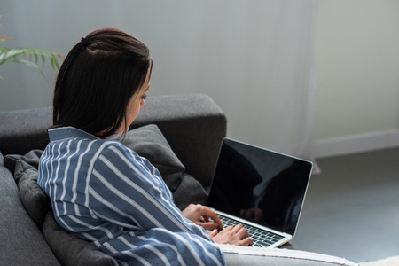 side view of woman using laptop with blank screen at homeの写真素材