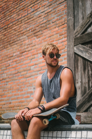 handsome skater sitting on side of pool in skateparkの写真素材