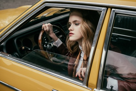 attractive stylish girl sitting in tero car and looking away