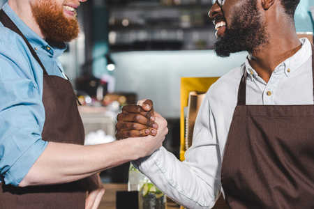 cropped image of two smiling owners of coffee shop shaking handsの写真素材