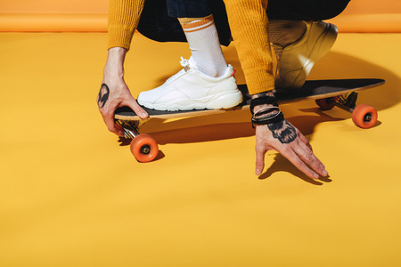 low section view of skateboarder in white sneakers on longboard, on yellowの写真素材