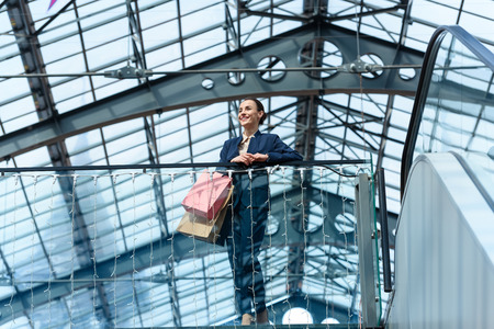 low angle view of attractive businesswoman leaning on railing in shopping mallの写真素材
