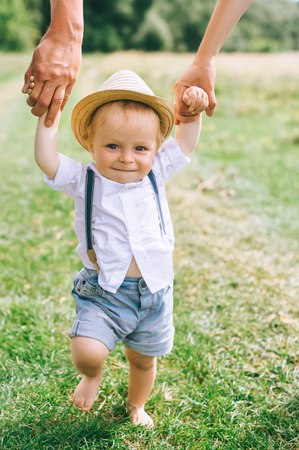 parents holding hands with little stylish son in straw hatの写真素材