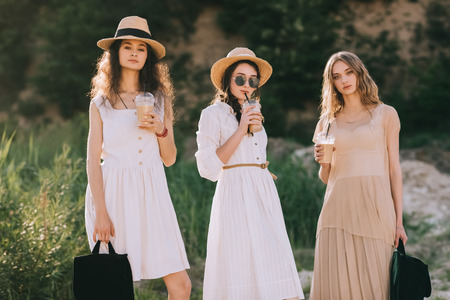 attractive stylish women in straw hats with coffee latte
