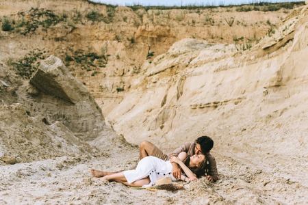 young tender couple hugging and lying in sand canyonの写真素材