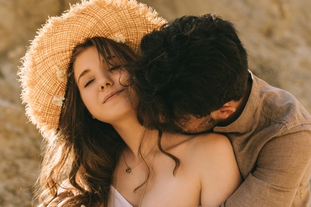 man kissing in neck his beautiful girlfriend in straw hatの写真素材