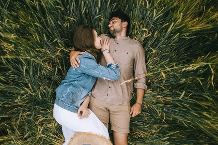 happy stylish couple lying in green grassの写真素材