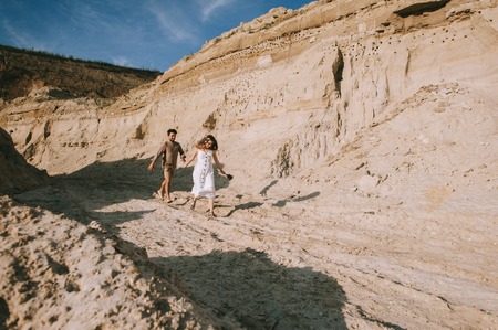 happy couple holding hands and running in sand canyon