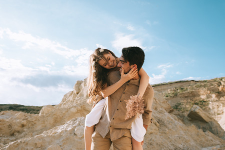 boyfriend piggybacking his happy girlfriend in canyon with blue skyの写真素材