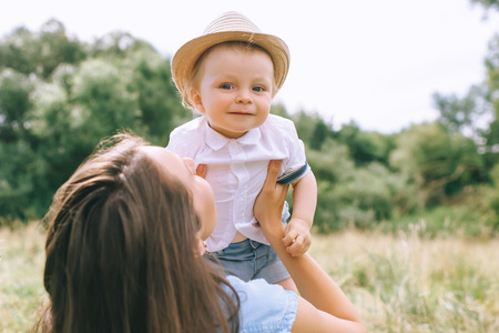 happy mother holding stylish baby boy in hands