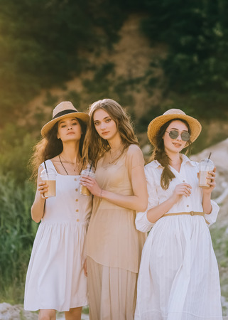 elegant pretty girls in straw hats holding plastic cups of coffee latteの写真素材