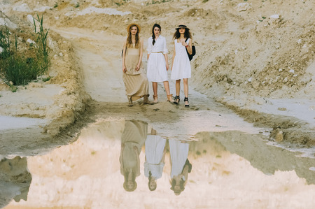 elegant stylish girls posing near big puddle in sandy canyonの写真素材