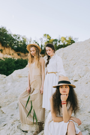 pretty girls in trendy dresses and straw hats posing in sandy canyonの写真素材