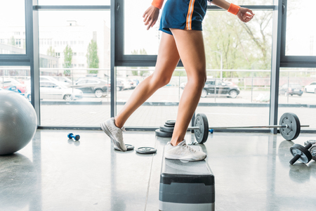 cropped image of sportswoman in wristbands exercising on step platform at gymの写真素材