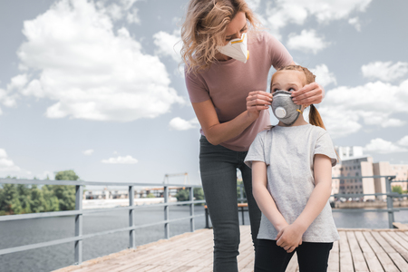 mother and daughter in protective masks on bridge, air pollution conceptの写真素材