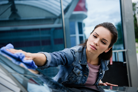 beautiful woman cleaning car at car wash with ragの写真素材
