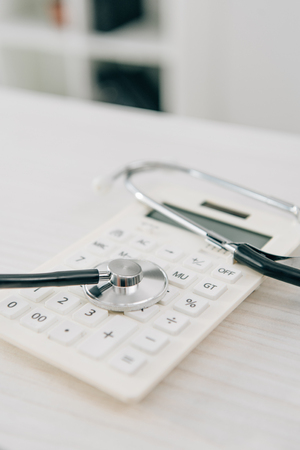 stethoscope lying on white calculator, health insurance conceptの写真素材