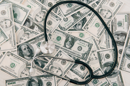 top view of stethoscope lying on dollar banknotes, health insurance conceptの写真素材