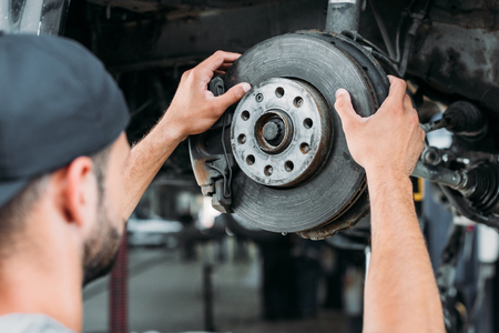selective focus of mechanic repairing car without wheel in workshopの写真素材