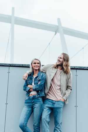 beautiful young couple leaning back on wall and looking awayの写真素材