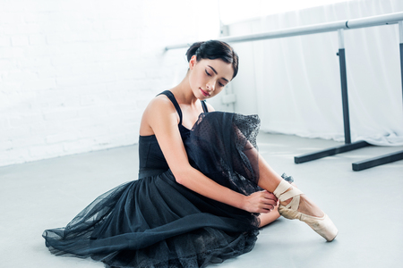beautiful tender young ballerina sitting and wearing pointeの写真素材