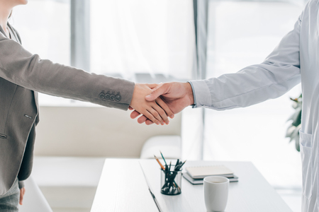 cropped image of patient and doctor shaking hands in clinicの写真素材