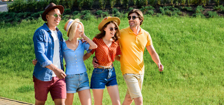 happy multicultural group of friends walking on street together on summer day