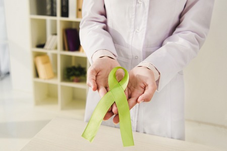 cropped view of doctor holding green ribbon - mental health dayの写真素材