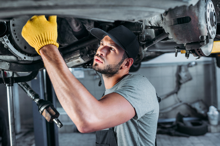 male mechanic fixing a car in auto repair shopの写真素材