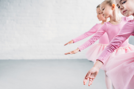 side view of graceful little ballerinas dancing together in ballet schoolの写真素材