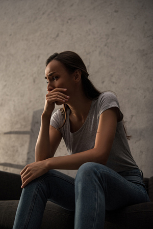 upset crying woman sitting on sofaの写真素材